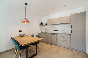 A modern kitchen with a wooden dining table, teal chairs, and a pendant light. - Holiday Apartment "Camping Passeier Bergliebe" with Mountain View & Wi-Fi (Saltaus)