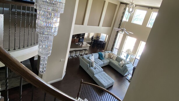A spacious living area with a large chandelier, a staircase, and a dining area. - Newly Listed Oasis (Pearland)