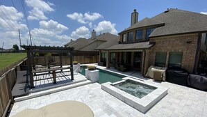 A backyard with a swimming pool, a pergola, and outdoor seating. - Newly Listed Oasis (Pearland)