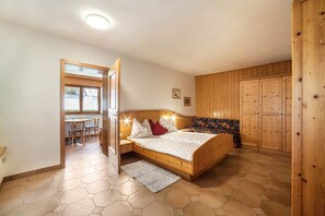 Une chambre à coucher avec un lit en bois, un petit bureau et une fenêtre.