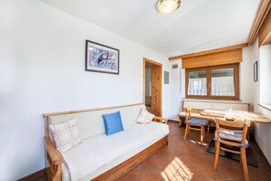 Une pièce chaleureuse avec un canapé en bois, une table à manger et des chaises.