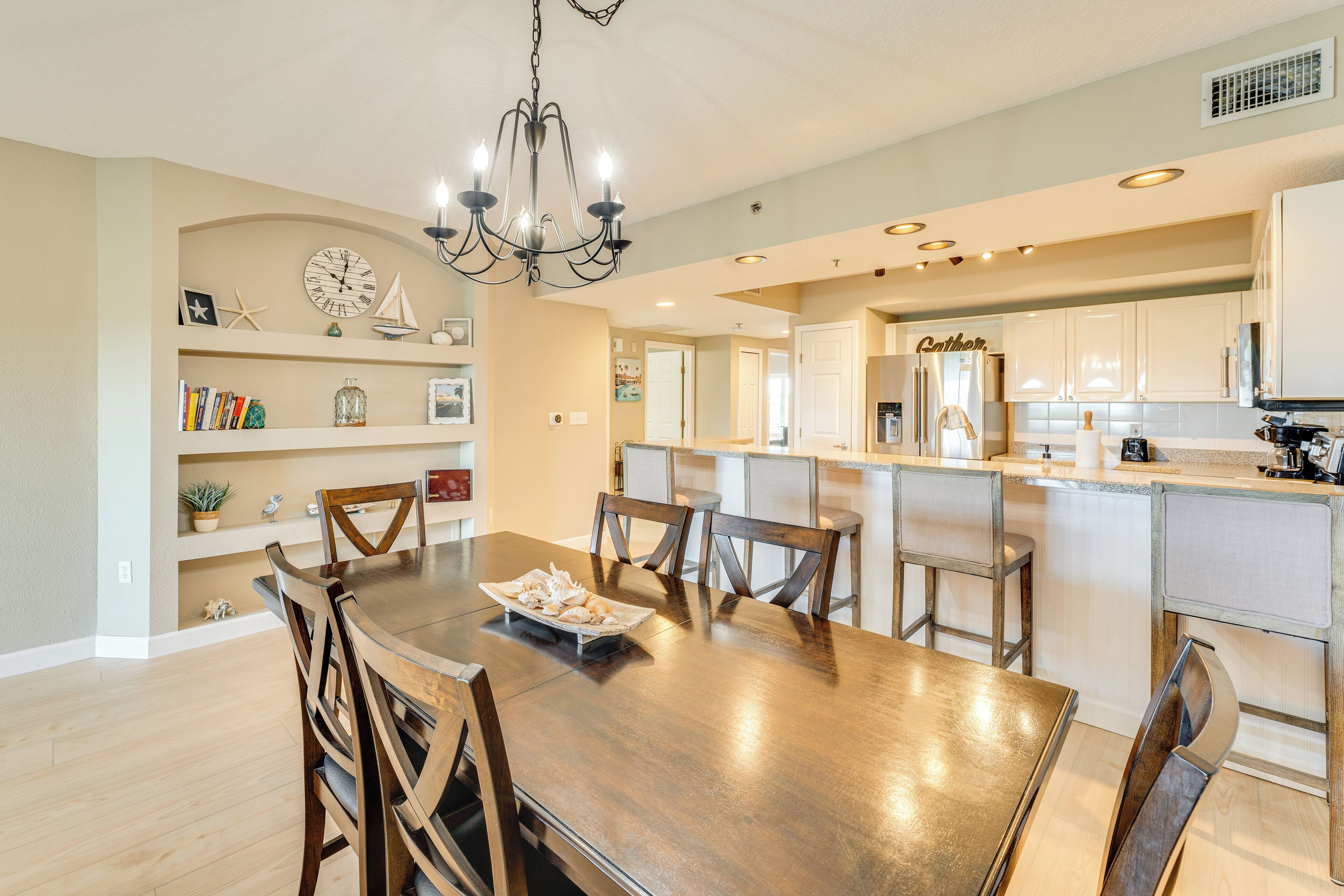 Une cuisine spacieuse avec des meubles blancs, un îlot central et un coin repas comprenant une table et des chaises en bois.