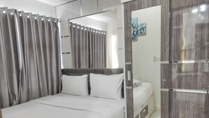 A hotel room with a bed, a mirror, and a wardrobe. - Best Deal And Cozy 2Br Vida View Apartment (Makassar)