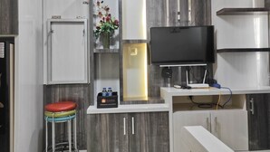 A modern kitchen with a built-in TV, a refrigerator, and a bar stool. - Best Deal And Cozy 2Br Vida View Apartment (Makassar)