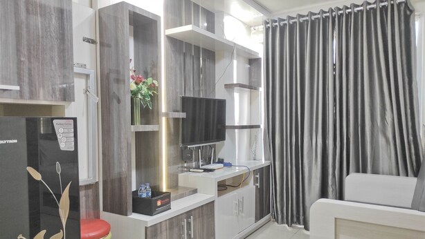 A modern kitchen with a refrigerator, a microwave, and a sink. There is a dining table with chairs and a sofa. - Best Deal And Cozy 2Br Vida View Apartment (Makassar)