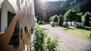 Un edificio con una reja de metal, un camino de grava y vehículos recreativos estacionados al fondo.