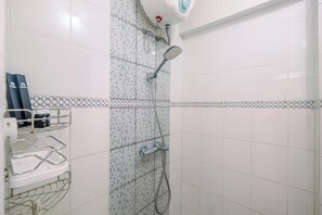 A bathroom with a shower, tiled walls, and a shelf with toiletries. - Simple And Cozy Living 2Br At Cibubur Village Apartment (Depok)