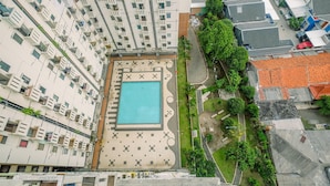 A high-rise building with multiple balconies, a central swimming pool, and surrounding greenery. - Simple And Cozy Living 2Br At Cibubur Village Apartment (Depok)
