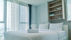 Een moderne hotelkamer met een groot bed, een houten plank met boeken en uitzicht door het raam.
