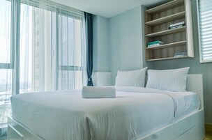 Une chambre d’hôtel moderne avec un grand lit, une étagère en bois remplie de livres et une vue par la fenêtre.