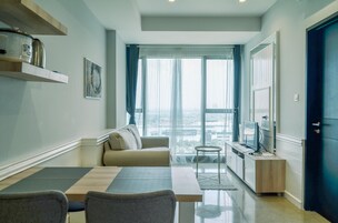 Un salon moderne comprenant un canapé, une table à manger et un coin cuisine avec un téléviseur.