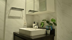Een badkamer met een wit wastafelmeubel, een spiegel en een plant in pot.