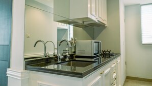 Een keuken met een zwart aanrecht, witte kasten, een roestvrijstalen afzuigkap en een magnetron.