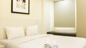 Een hotelkamer met een net opgemaakt bed, een ingelijst foto op de muur en een raam met jaloezieën.