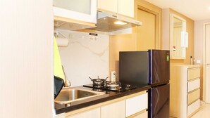 Une cuisine de taille réduite, équipée d’une cuisinière, d’un évier et d’un réfrigérateur.