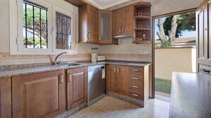 Une cuisine avec des meubles en bois, un lave-vaisselle et une fenêtre donnant sur les arbres.