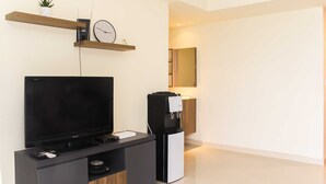 Una sala de estar moderna con un televisor de pantalla plana, una cafetera y un reloj en un estante.