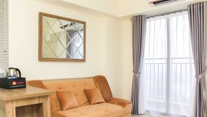 Una sala de estar moderna con un sofá, una mesa de centro y un amplio ventanal con cortinas.
