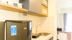 Una cocina compacta con refrigerador de acero inoxidable, un lavamanos y una encimera de madera.