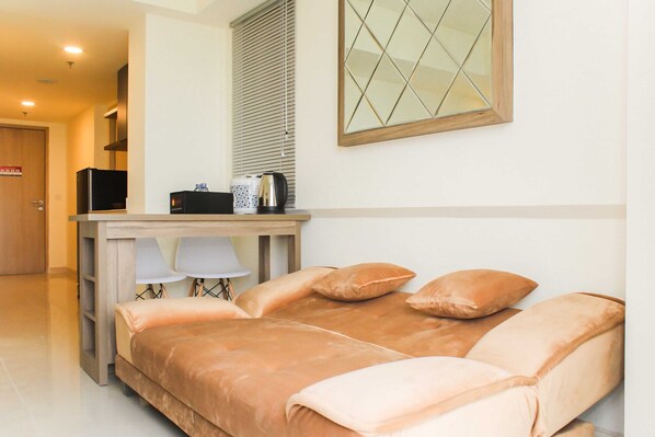 A bedroom with a bed, a desk with a chair, a television, and a window with blinds.