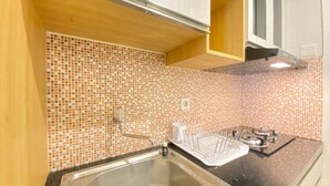 A kitchen with a tiled backsplash, a stainless steel sink, and a gas stove. - Comfy And Relax 1Br Apartment At Parahyangan Residence Near Unpar (Bandung)