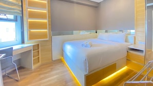 A modern hotel room with a neatly made bed, a desk, and a chair. - Comfy And Relax 1Br Apartment At Parahyangan Residence Near Unpar (Bandung)