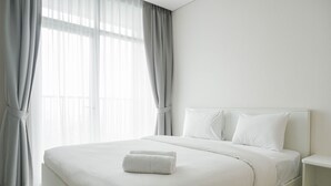 Une chambre d’hôtel moderne avec un grand lit, du linge de lit blanc et un lit parfaitement fait, agrémenté d’une serviette.
