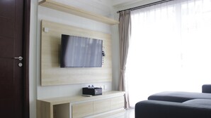 Un salon moderne avec un téléviseur à écran plat fixé à un mur en bois, un banc intégré en dessous et une grande fenêtre avec des rideaux.