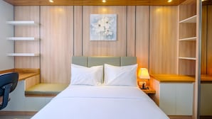 A modern hotel room with a bed, bedside table, lamp, and a wall-mounted shelf. - Good Deal Studio At Evenciio Apartment Margonda Near Ui (Depok)