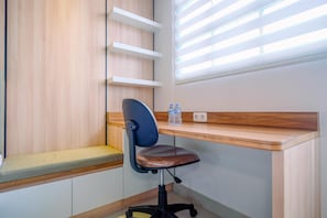 A modern office space with a wooden desk, a cushioned chair, and built-in shelves.