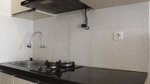 A kitchen with a black countertop, stainless steel sink, and a gas stove. - Pool View 2Br Apartment At The Jarrdin Cihampelas (Bandung)