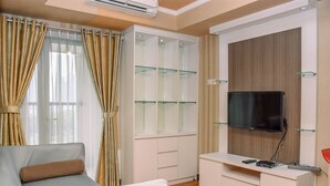 A modern living room with a sofa, a glass-fronted cabinet, and a mounted TV. - Nice And Homey 1Br At The Wave Kuningan Apartment (Jakarta)