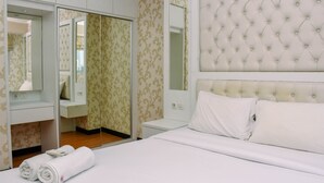 A hotel room with a bed, a nightstand, a mirror, and a wardrobe. - Nice And Homey 1Br At The Wave Kuningan Apartment (Jakarta)