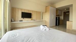 Habitación de hotel con una cama grande, un televisor de pantalla plana en la pared, un minibar y una cocina independiente.
