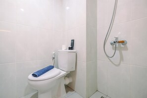 A bathroom with a toilet, a towel, and a shower. - Elegant Studio At Evenciio Apartment Margonda (Depok)