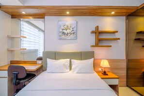 A modern hotel room with a bed, bedside table, lamp, and a painting on the wall.