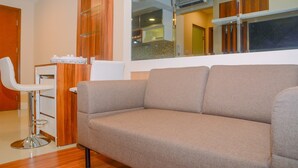 Ein modernes Wohnzimmer mit einem grauen Sofa, einem weißen Sessel und einem Holzschrank.