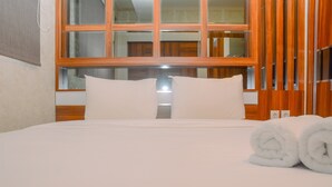 Ein ordentlich bezogenes Bett mit weißen Leinen und Kissen, ein Fenster mit Holzrahmen und eine Holzwandverkleidung.