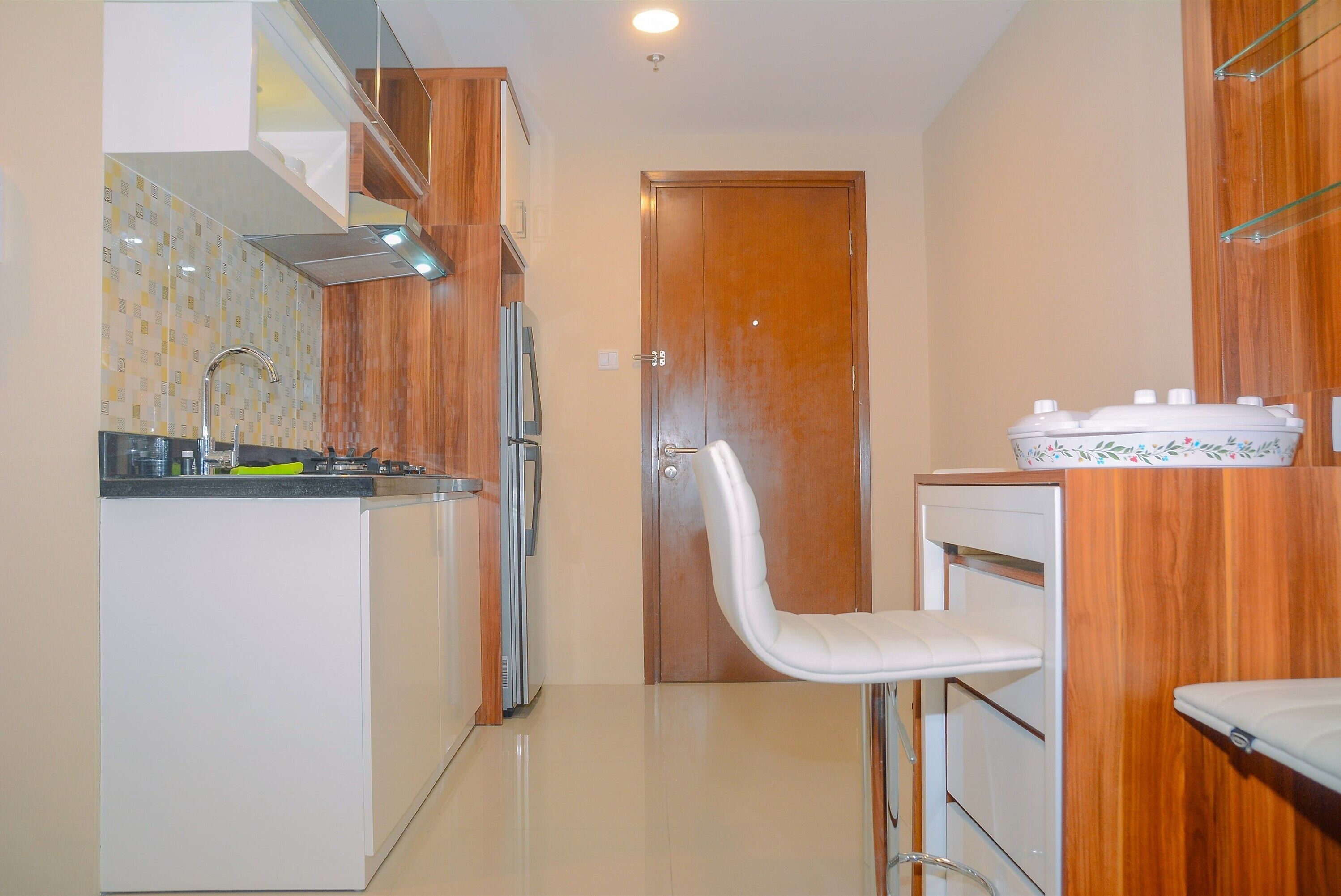 A compact kitchen with a built-in stove, a sink, and a white chair.