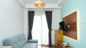 A modern room with a sofa, a wooden cabinet, a TV mounted on the wall, and a window with curtains.