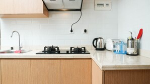 A kitchen with a gas stove, a kettle, a coffee maker, and a sink.