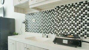 A modern kitchen with a checkered backsplash, a built-in sink, and a portable gas stove.
