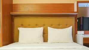 Ein Hotelzimmer mit einem hölzernen Kopfteil, zwei weißen Kissen und einer weißen Bettdecke.