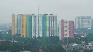 Ein Hochhaus mit mehreren Stockwerken, umgeben von Grünflächen und weiteren Gebäuden.
