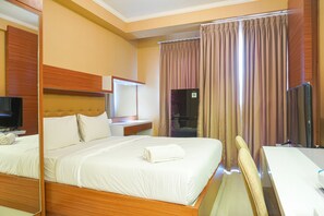 Ein Hotelzimmer mit einem großen Bett, einem Schreibtisch, einem Sessel, einem Fernseher und einem Spiegel.