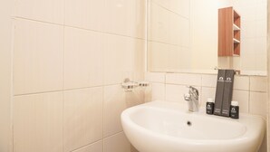 Ein Badezimmer mit einem weißen Waschbecken, einem Spiegel und einem Holzkabinentchen.