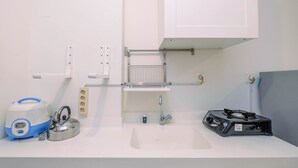 Un baño con lavamanos, hervidor de agua, calentador portátil y cambiador para bebés.