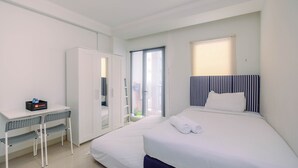 Una habitación de hotel con cama, escritorio, armario y vistas al exterior.