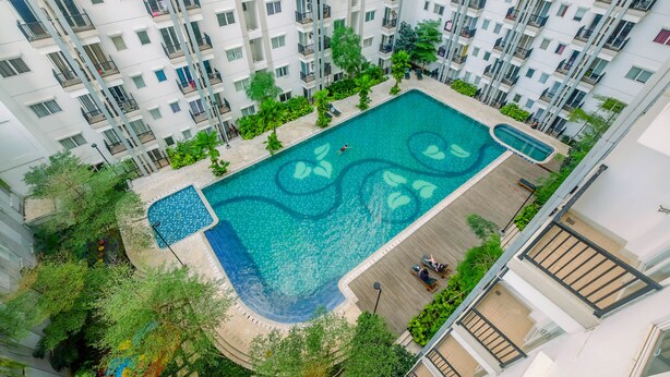 Un edificio residencial alto con piscina en la azotea rodeada de vegetación.