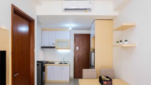 A compact living space with a kitchenette, a dining area, and a TV.